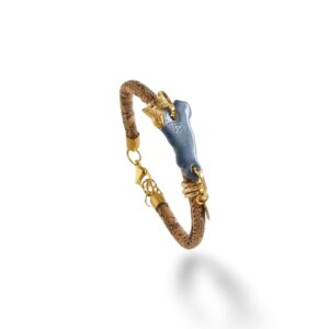 Il bracciale con “Sicilia” è realizzato in porcellana smaltata, successivamente lustrato a terzo fuoco con applicazione a pennello in oro. E’ montato su cordoncino di sughero ocra screziato; chiusura e gancio in acciaio inossidabile, elementi di raccordo in alluminio dorato.